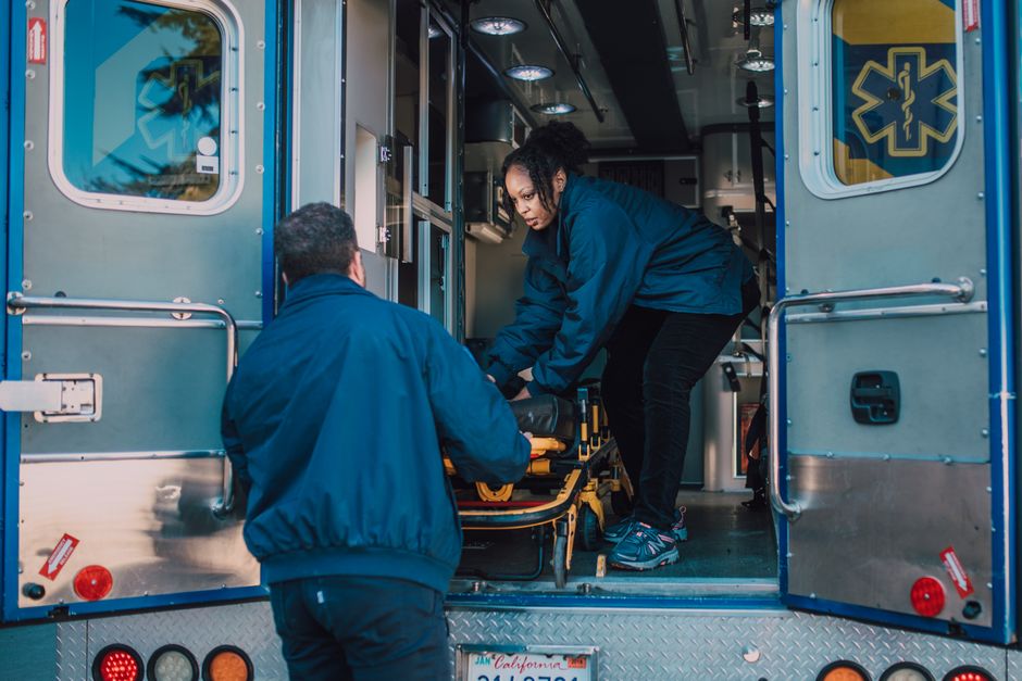 Paramedics loading a stretcher into an ambulance, illustrating ambulance ride cost without insurance